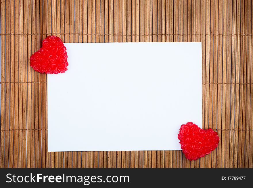 Two red hearts with paper card on wooden background