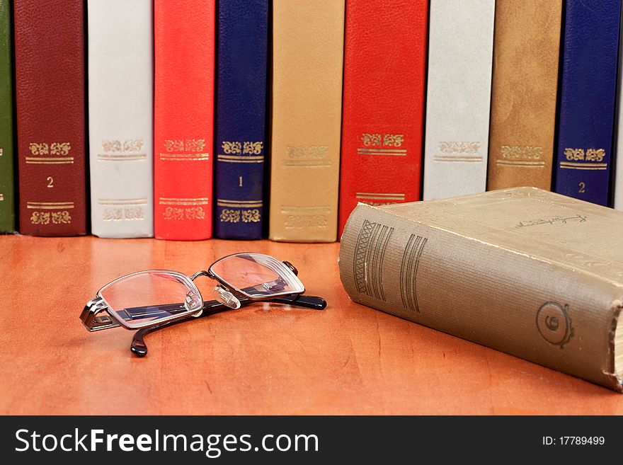 Glasses with old hardcover books on bookshelf