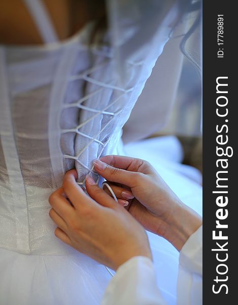 Hands helping with bride's white corset. Hands helping with bride's white corset