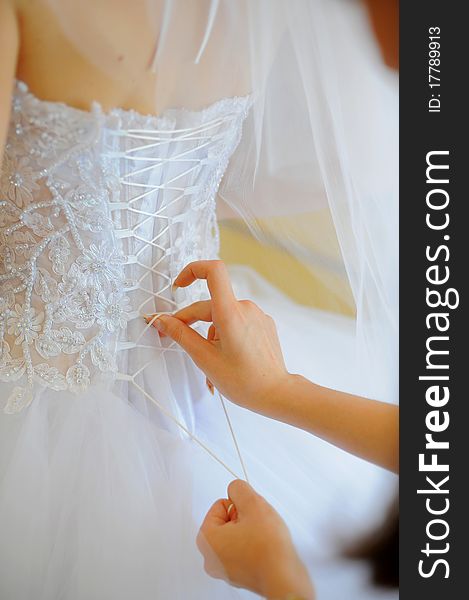Hands helping with bride's white corset. Hands helping with bride's white corset