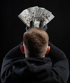 Man In Black Hoody Holding Pack Of American Dollars Over Black Background Stock Image