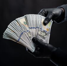 Man In Black Gloves Holding Pack Of Dollars Over Black Background Stock Photo