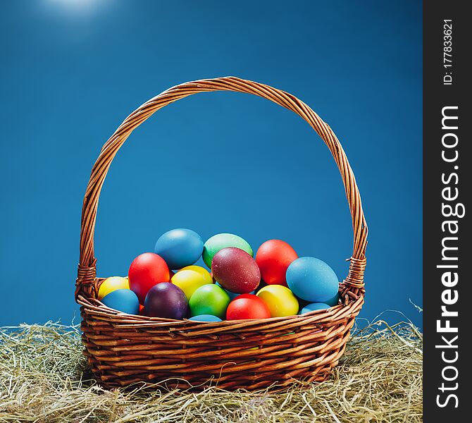 Easter basket with multicolor eggs, blue background, close-up view