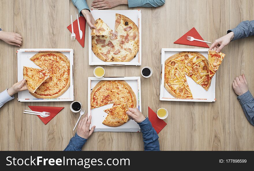 Group of friends having a pizza party at home and enjoying together, they are holding pizza slices, flat lay