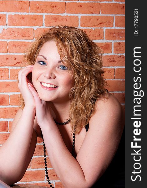 Portrait of charming  young woman staying near brick wall