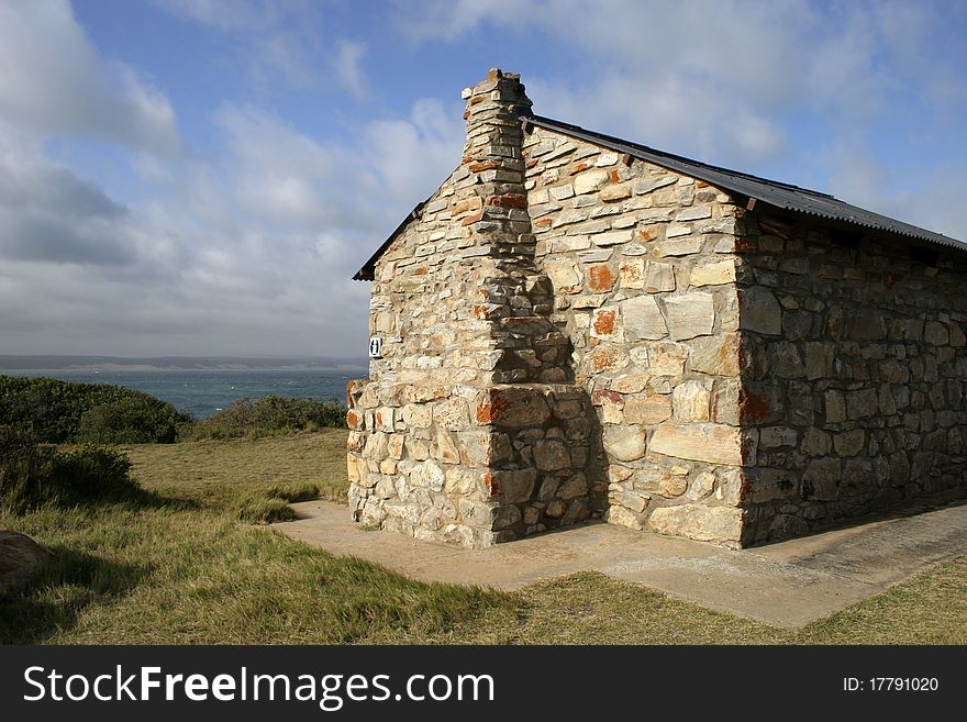 Stone building overlooking sea with blue sky and clouds
