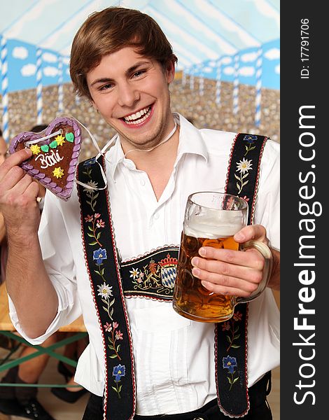 Handsome bavarian man holding a beer and a gingerbread heart. Handsome bavarian man holding a beer and a gingerbread heart