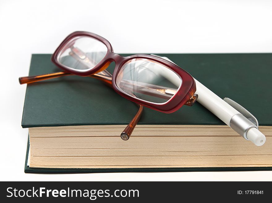 Glasses on book and pen isolated in white