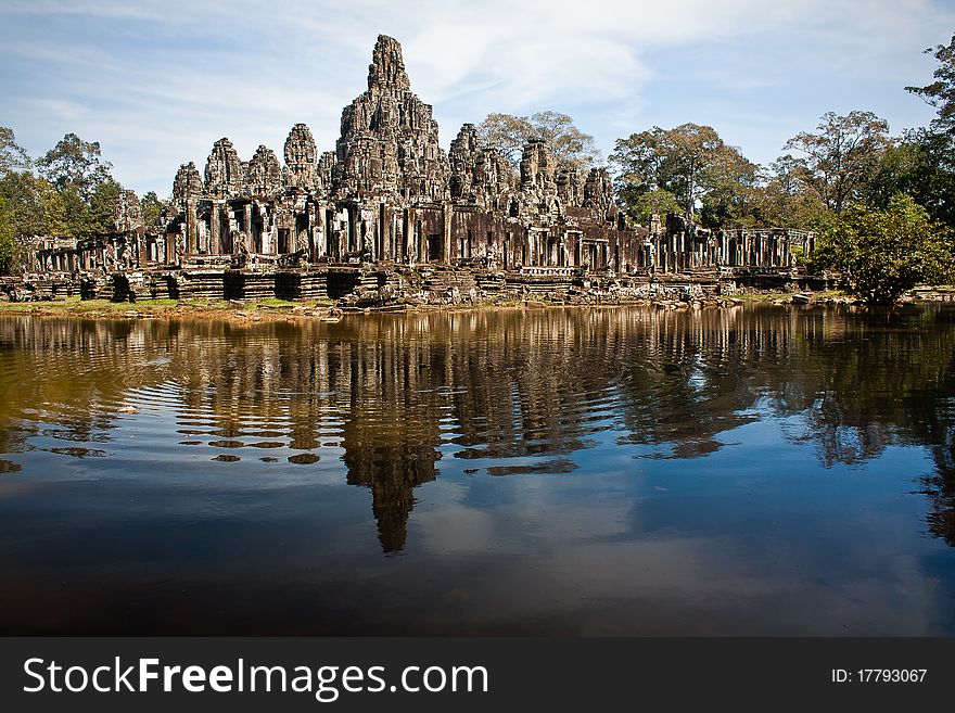 Old ruined temple near Angkor Wat. Deep blue lake in foreground with ripples and reflection of stone structure in mid ground. Old ruined temple near Angkor Wat. Deep blue lake in foreground with ripples and reflection of stone structure in mid ground