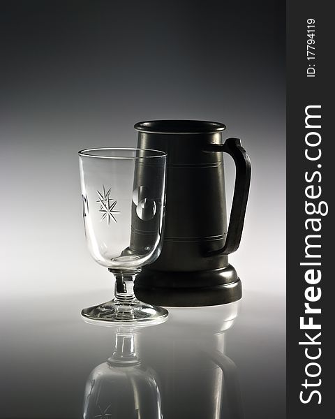 Pewter mug and wine glass on reflective background. Pewter mug and wine glass on reflective background