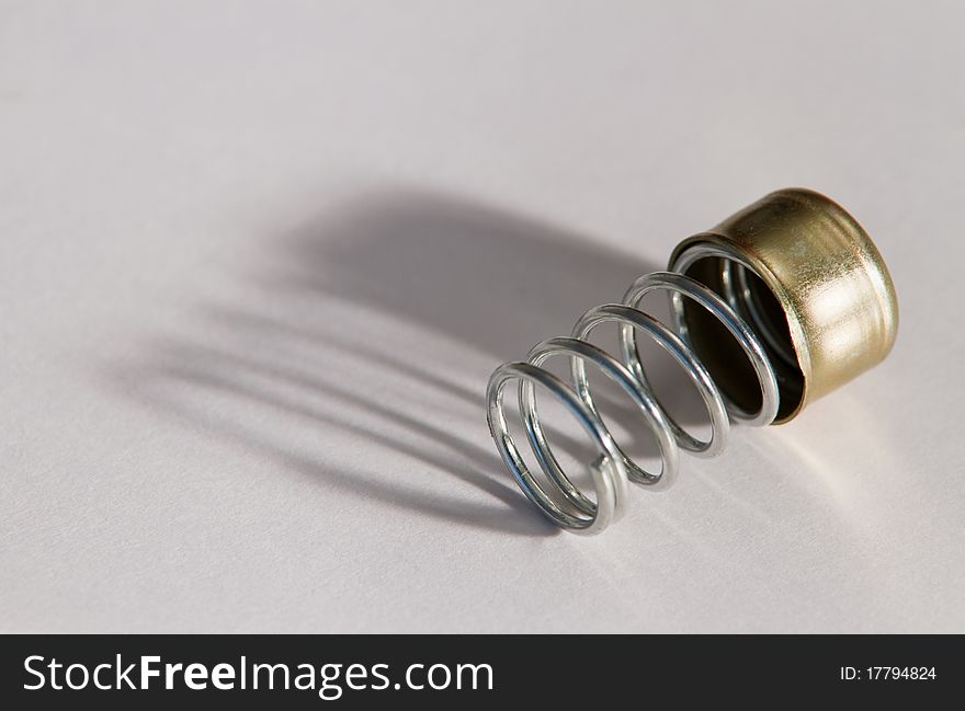 Close-up of a steel spring on light background with reflections of light