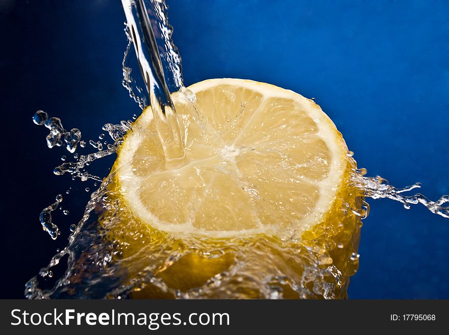 Water splash on lemon on the blue baclground.