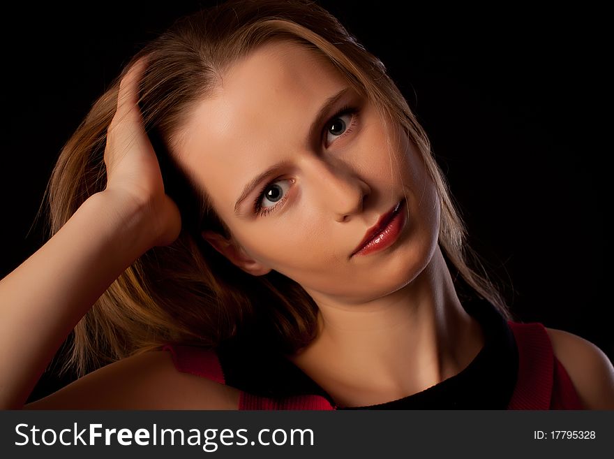 Beautiful young woman playing with her hair looking straight in camera on black background