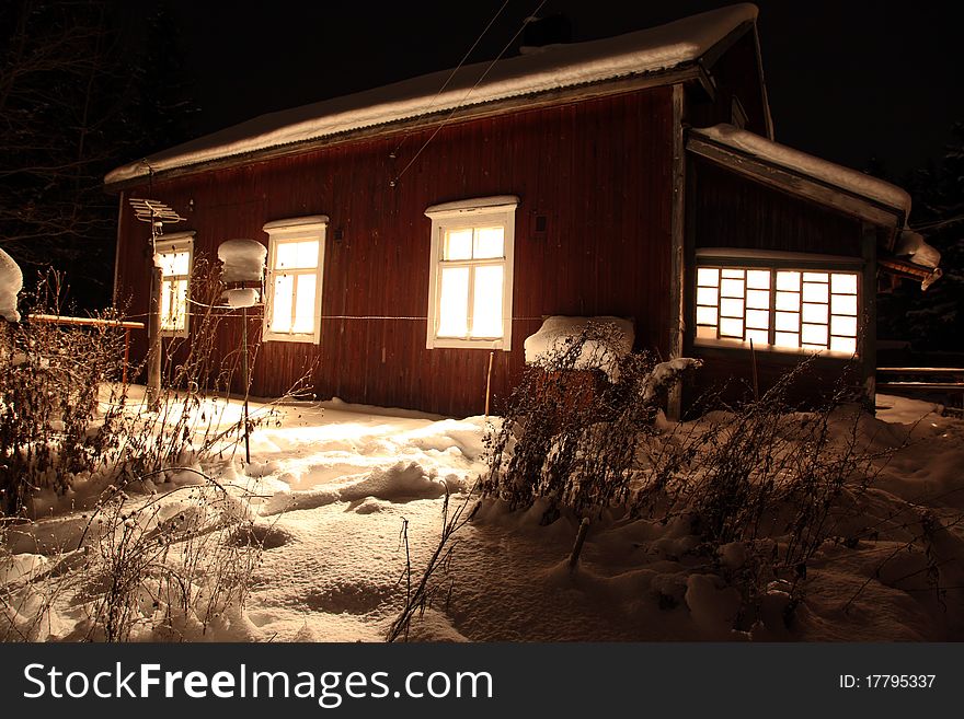 Classic Red wooden Finnish house in winter covered with snow in deep night, North Europe