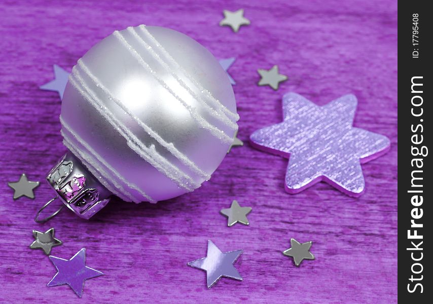 Bright glass bauble ornament and stars. Purple colors background. Bright glass bauble ornament and stars. Purple colors background