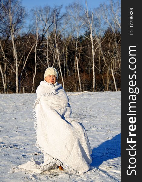 Adult woman in white on a snowy background, bright sunny frosty day