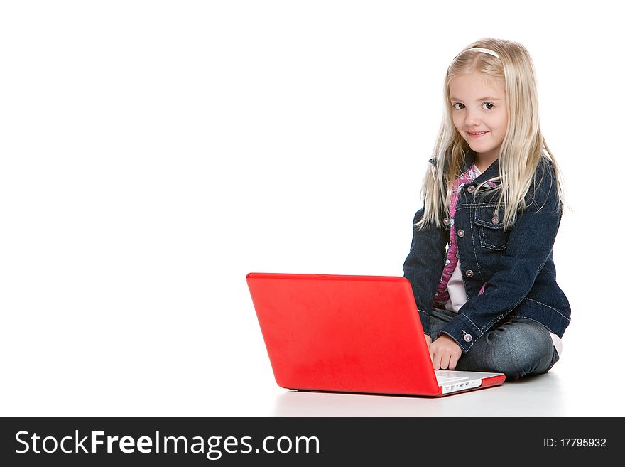 Cute little girl sitting down using a laptop isolated on white background. Cute little girl sitting down using a laptop isolated on white background