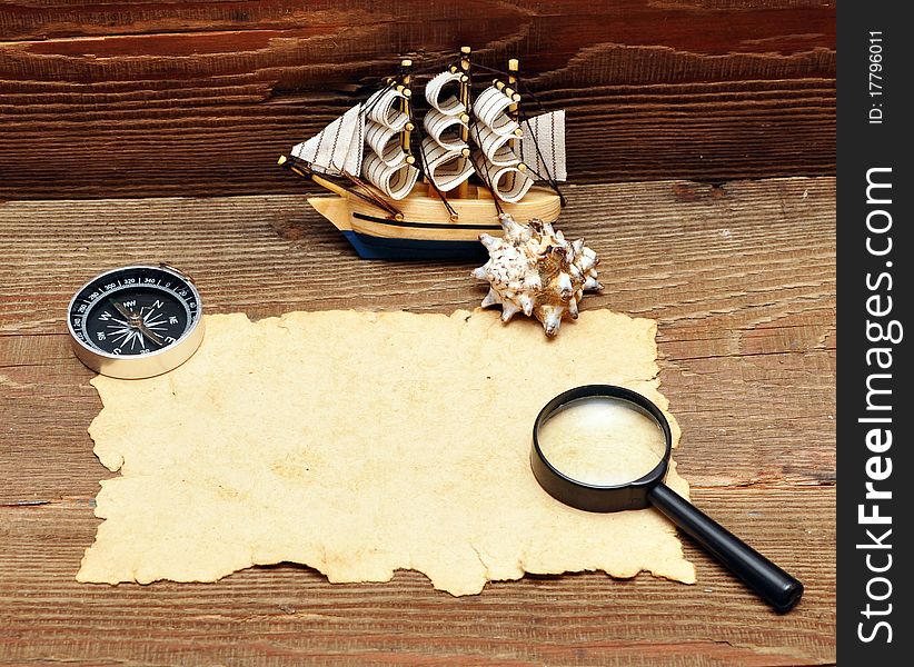 Model classic boat, compass and rope on wood background