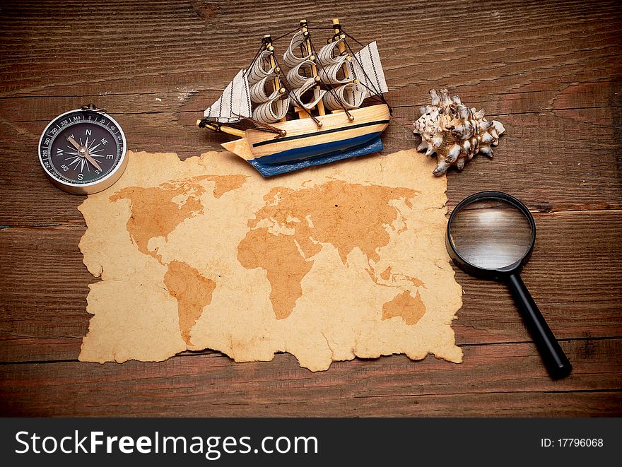 Model classic boat, compass and loupe on wood background