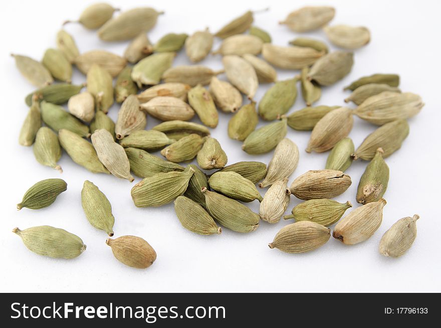 Green cardamon seeds isolated on a neutral background with shallow depth of field.