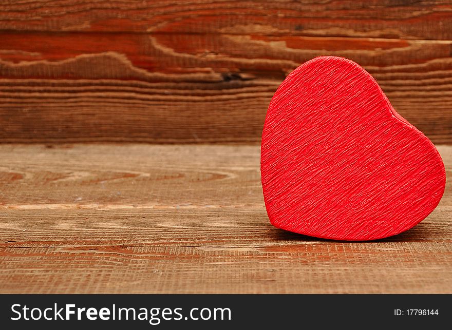 Red box in heart shape on wood background