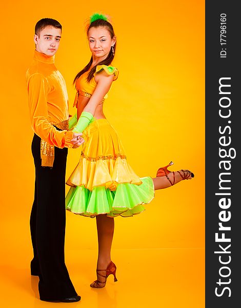 Charming young  pair in good-looking suits on a yellow background