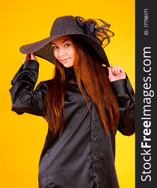 Charming young  woman in a hat on a yellow background