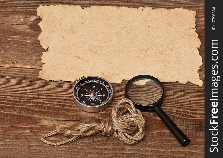 Old paper, compass and magnifying glass on wood background