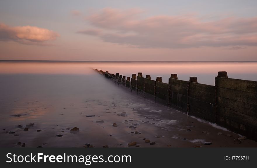 A groyne juts out into the sea on a peaceful spring evening. Photograph taken with a neutral density filter to enable long exposure.