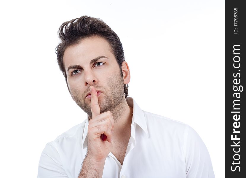 Man in white shirt doing a silence gesture with forefinger - isolated on white. Man in white shirt doing a silence gesture with forefinger - isolated on white