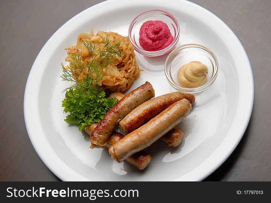 Grilled sausages with sauerkraut and sauce on a plate