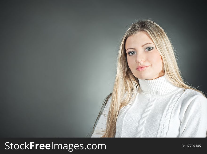 Beautiful blond girl wearing in the white sweater on the black background
