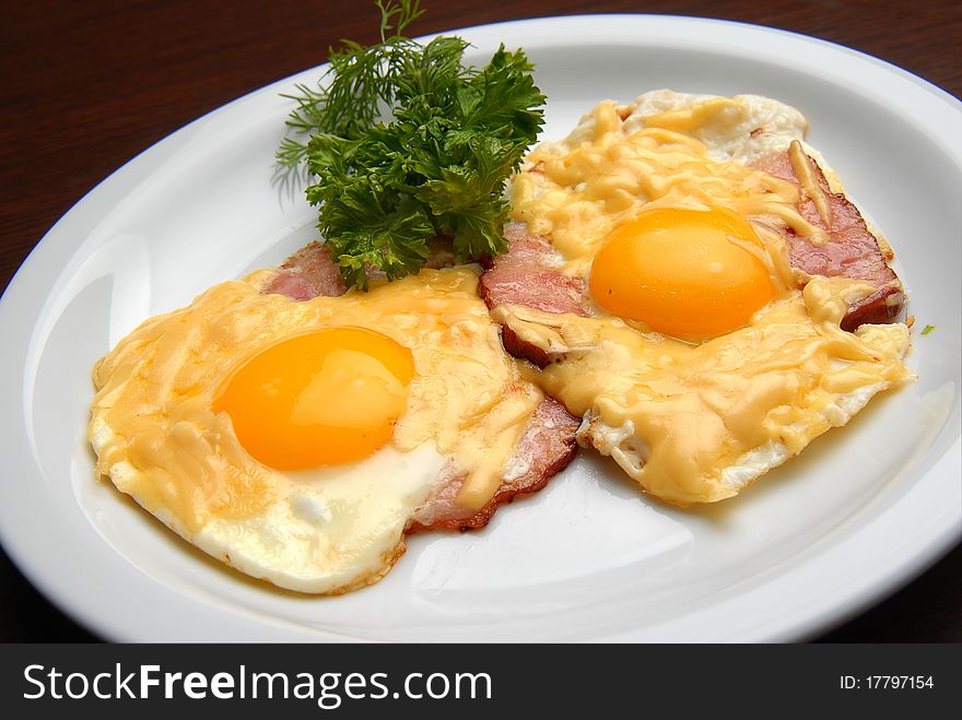 Fried eggs with ham and cheese on a plate. Fried eggs with ham and cheese on a plate