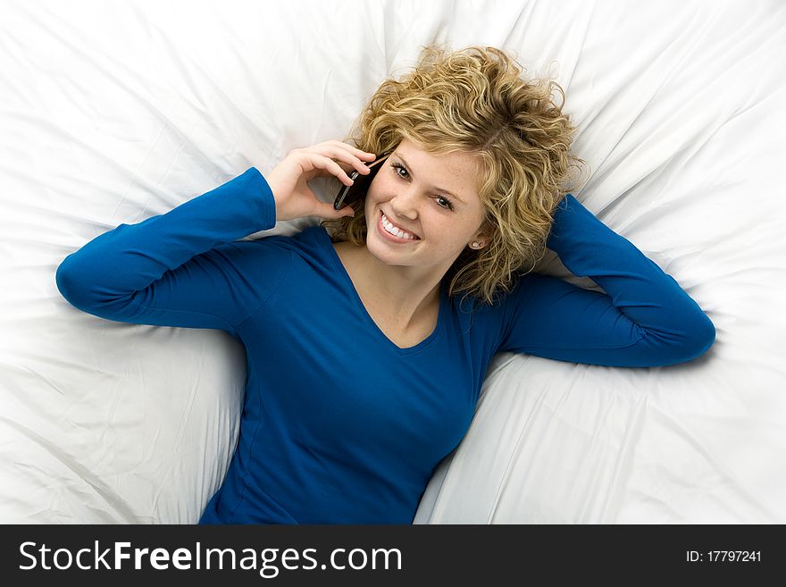 Beautiful teenage girl lying down talking on a cell phone