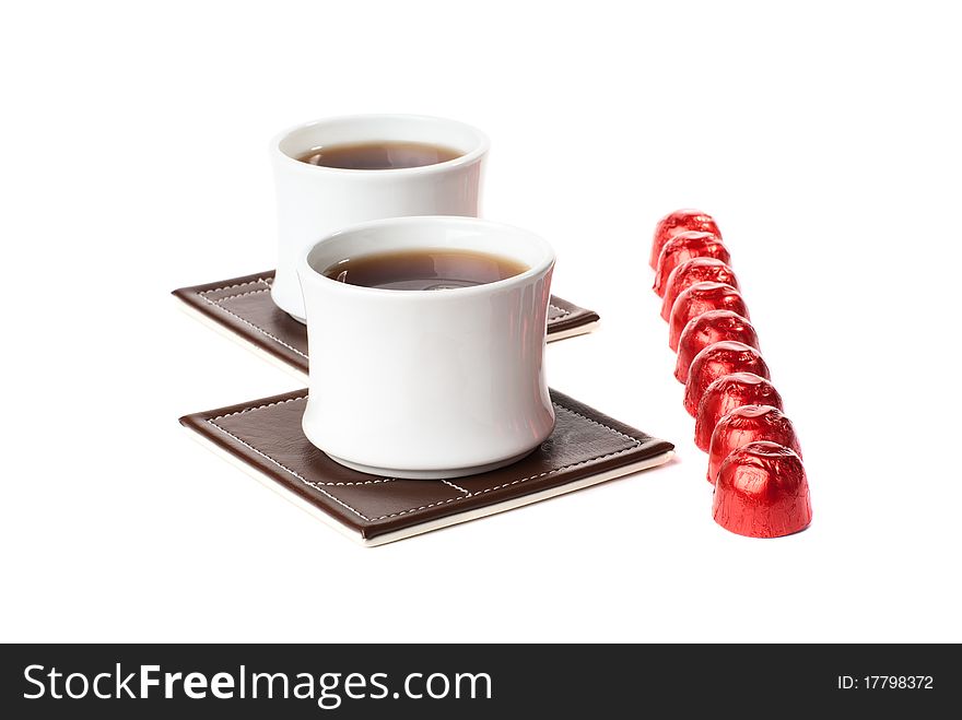 Two cups of tea on the table mat with sweets. Isolated on white background. Two cups of tea on the table mat with sweets. Isolated on white background.