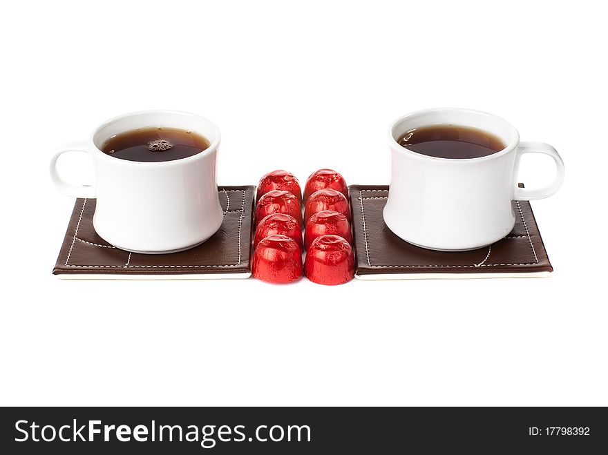 Two tea cups ot table mats with sweets. Isolated on White background. Two tea cups ot table mats with sweets. Isolated on White background.