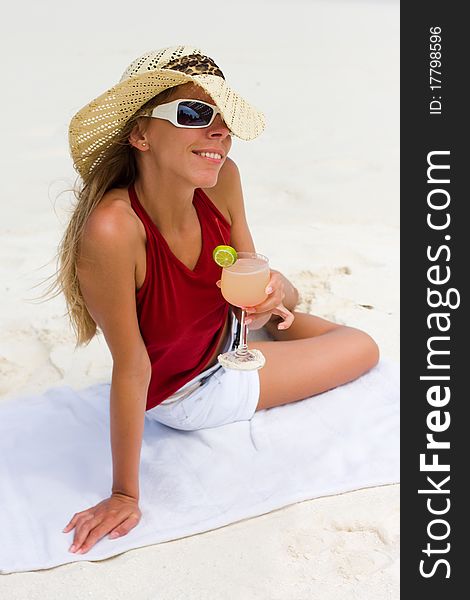 Lady on a tropical beach with cocktail in a hand