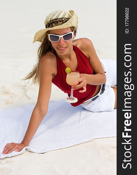 Lady on a tropical beach with cocktail in a hand