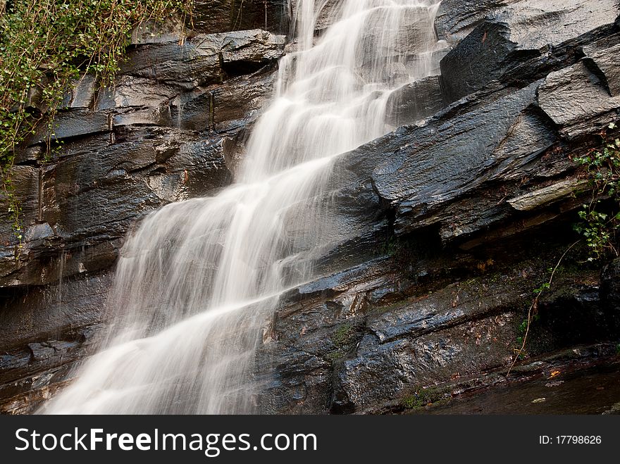 The side view of a waterfall over rocks and nature. The side view of a waterfall over rocks and nature