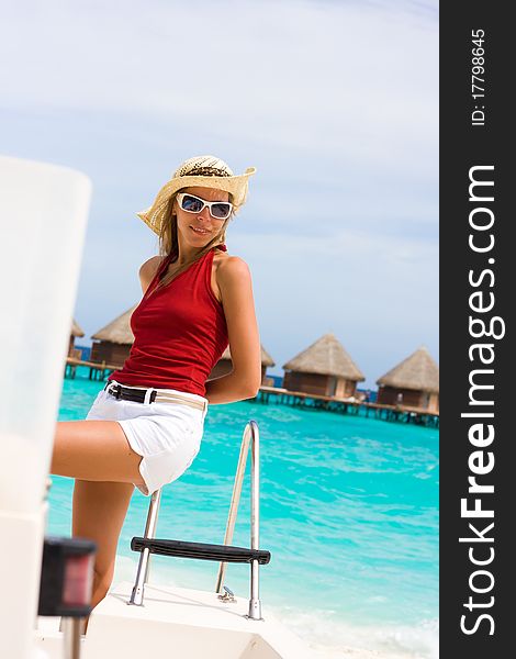 Lady stands abovedeck white yacht at a tropical coast