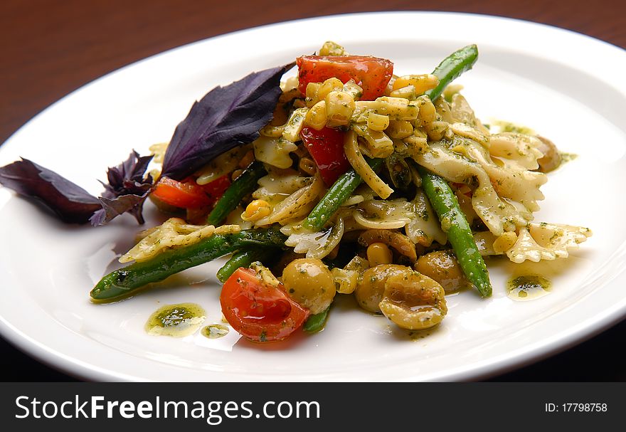 Pasta salad, vegetables, olives and butter on a plate