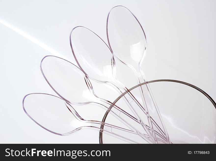 Transparent plastic spoons on a luminous background