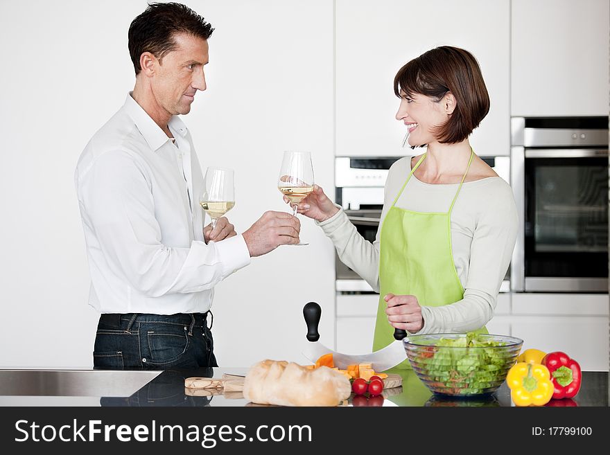 Happy Couple Toasting With Glass Of Wine while preparing dinner