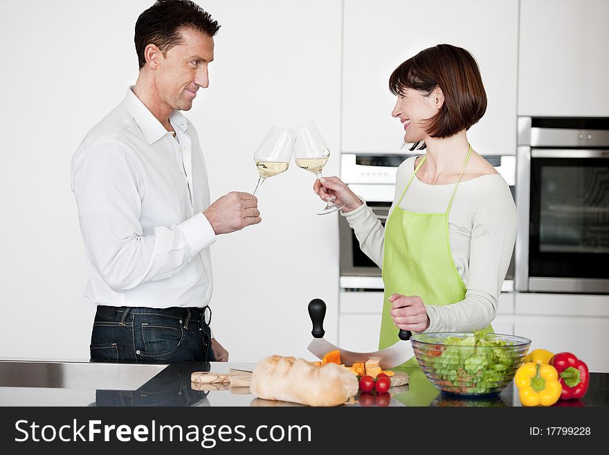 Happy Couple Toasting With Glass Of Wine while preparing dinner