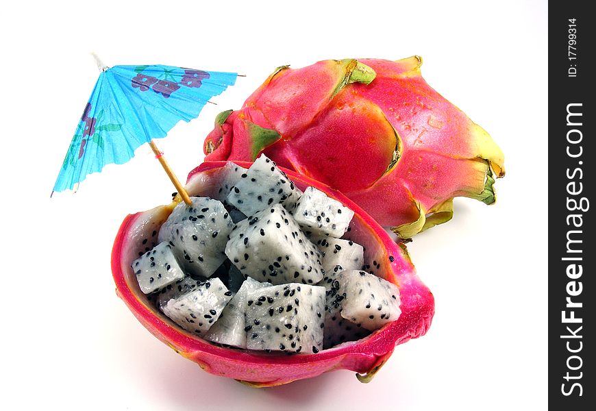 A diced dragon fruit with a sun umberella on a white background. A diced dragon fruit with a sun umberella on a white background