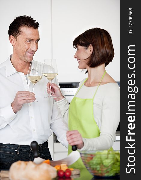 Happy Couple Toasting With Glass Of Wine while preparing dinner