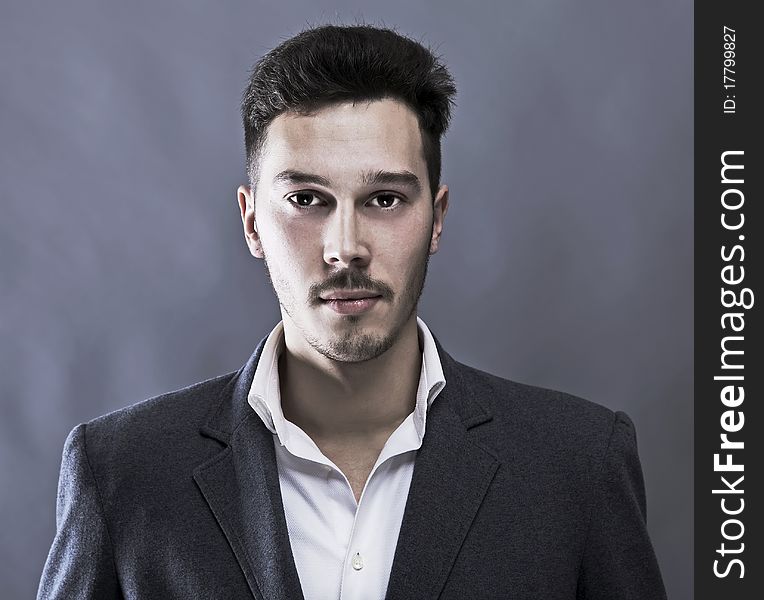 Young attractive man in suit on gray background