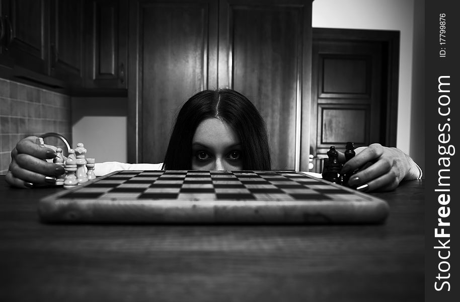 Frightened girl looking out of chess board. Photo.