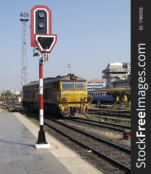 Railway signal showing red light and old yellow diesel electric locomotive at Hua Lampong railway station in Bangkok, Thailand. Railway signal showing red light and old yellow diesel electric locomotive at Hua Lampong railway station in Bangkok, Thailand.