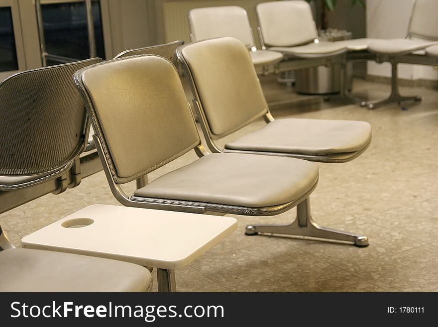 A couple of chairs in the waiting room of an airport departure gate. A couple of chairs in the waiting room of an airport departure gate